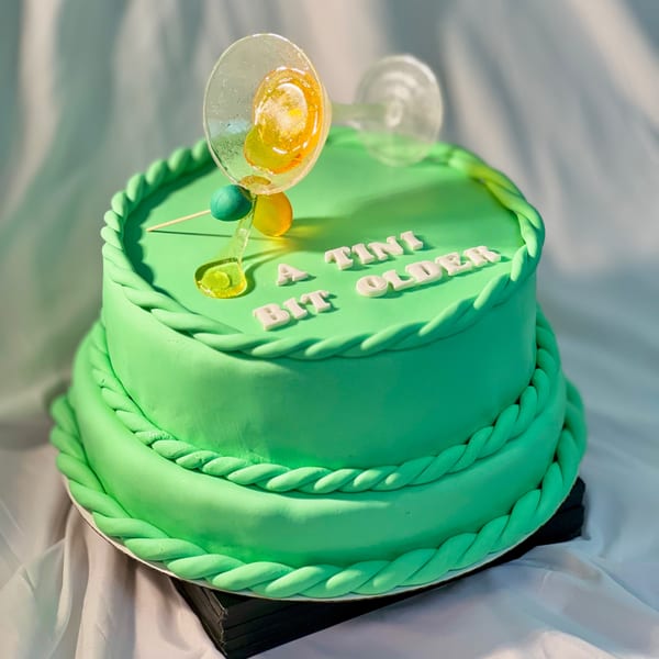 Two-tiered green cake with "A TINI BIT OLDER" text and martini glass decorations.