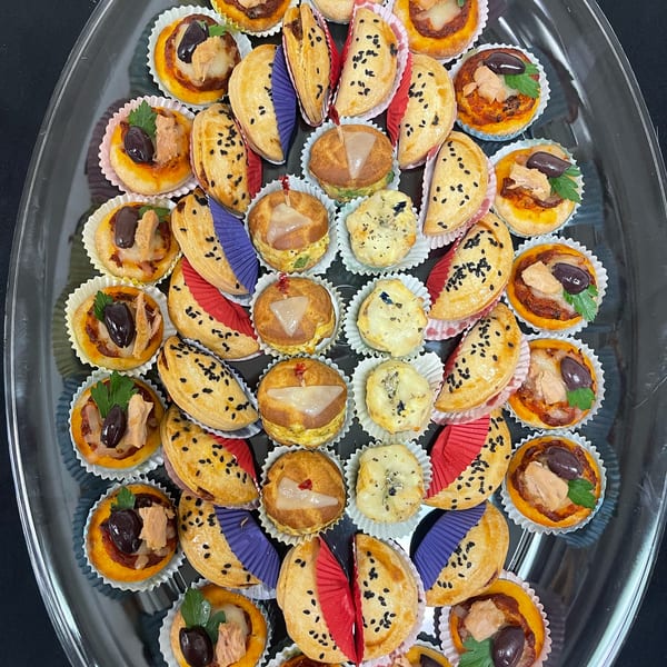A clear platter filled with various Brioche de Paris savory mini pastries and tarts.