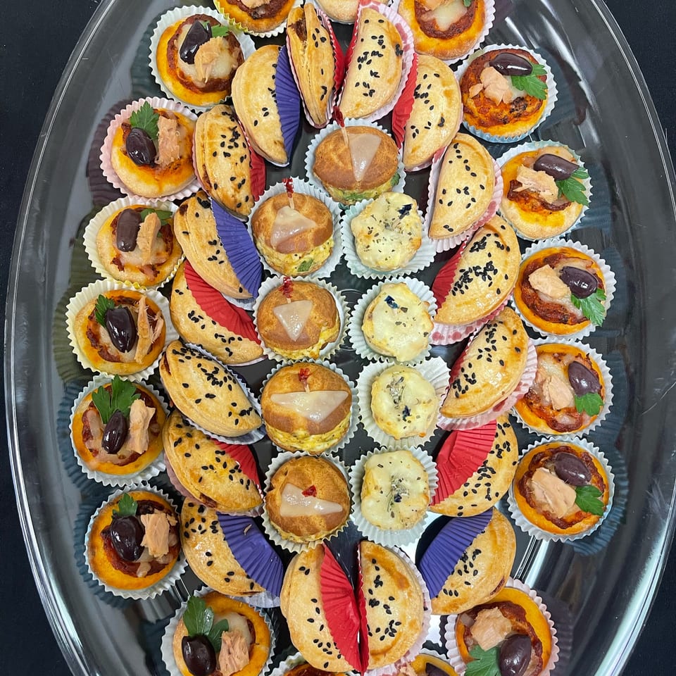 A clear platter filled with various Brioche de Paris savory mini pastries and tarts.