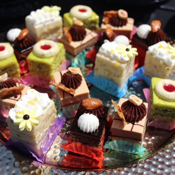 A silver tray holds an assortment of colorful Brioche de Paris mini cakes and pastries.